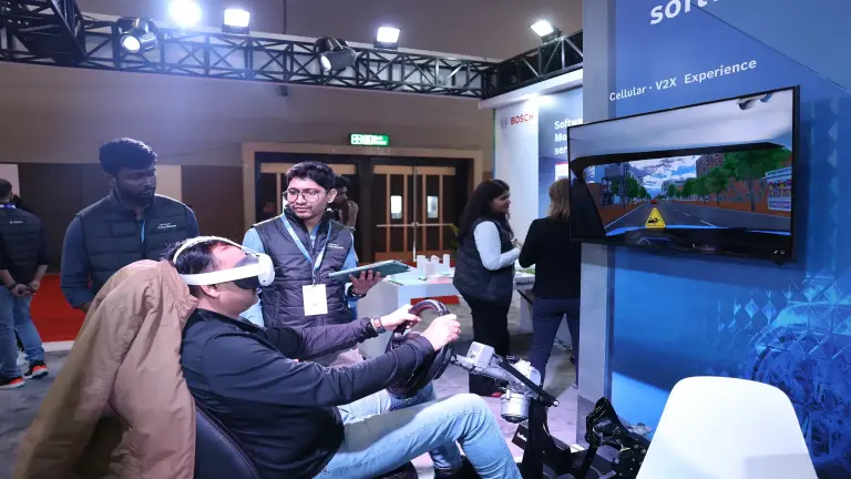 Ein Mann erlebt eine V2X-Erfahrung mit einem VR-Headset und einem Lenkrad am Bosch-Stand.
