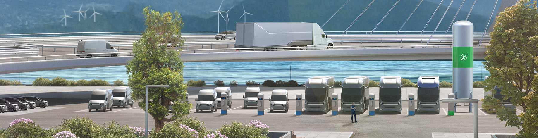 Electric commercial vehicles at a charging depot with wind turbines in the background represents sustainable transport solutions.