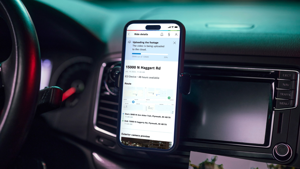 Smartphone, das an an einem Armaturenbrett montiert ist, Bildschirm zeigt das RideCare companion Fahrer-Portal mit Details zu einer Fahrt