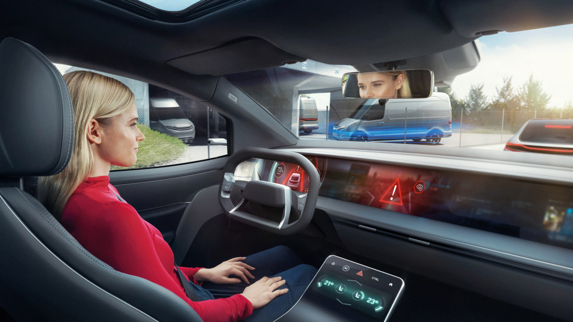 Eine Person sitzt in einem modernen, mit Touchscreens ausgestatteten Fahrzeuginterieur.